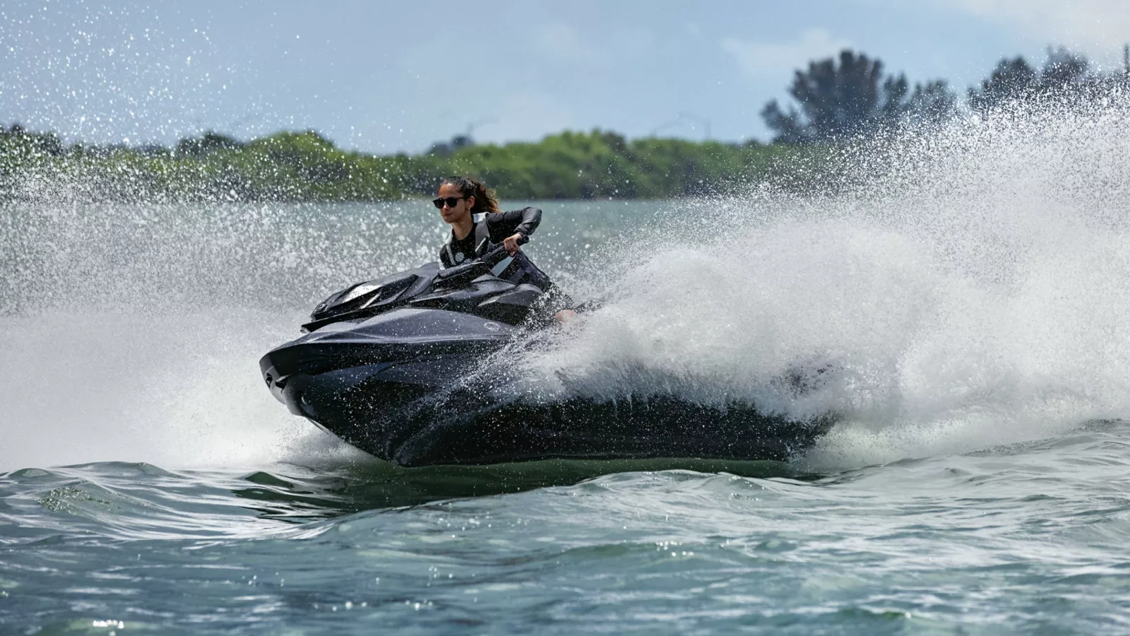 A black Sea-Doo personal watercraft carving through the water, throwing up spray